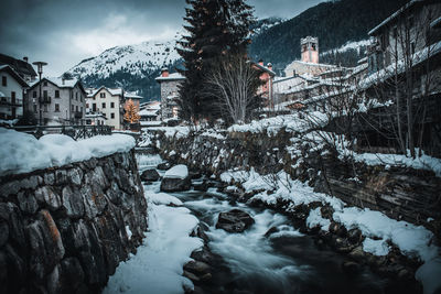 Snow covered trees and buildings against mountain