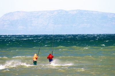 People fishing in sea against sky