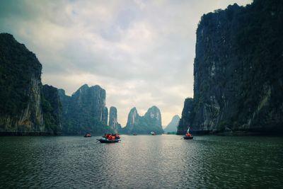 People kayaking on lake by mountains 