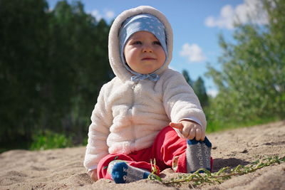 Full length of cute baby boy sitting on sand at beach