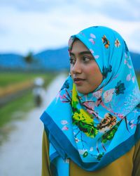 Portrait of young woman standing against sky