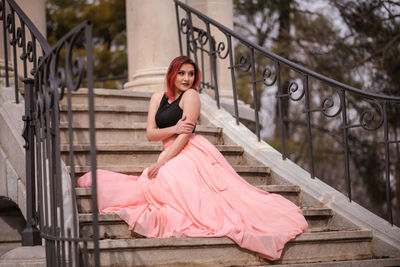 Portrait of woman sitting on railing