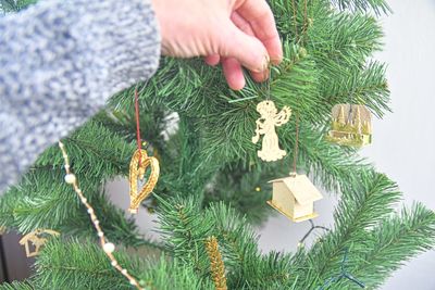 Decorating the christmas tree, holding some decoration in his hand. horizontal view several objects