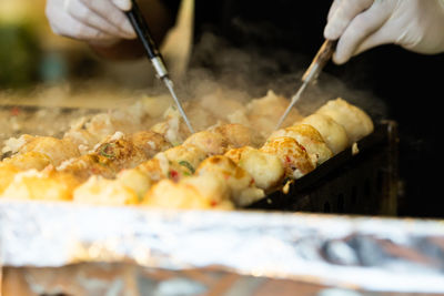 Close-up of person preparing meat on barbecue grill