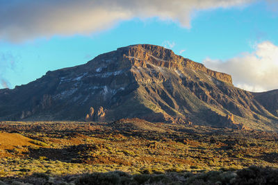 Scenic view of mountain range against cloudy sky