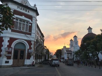 Street amidst buildings against sky during sunset