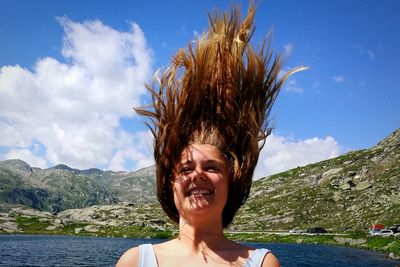Smiling girl with tousled hair against lake