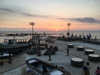 Boats moored at harbor during sunset