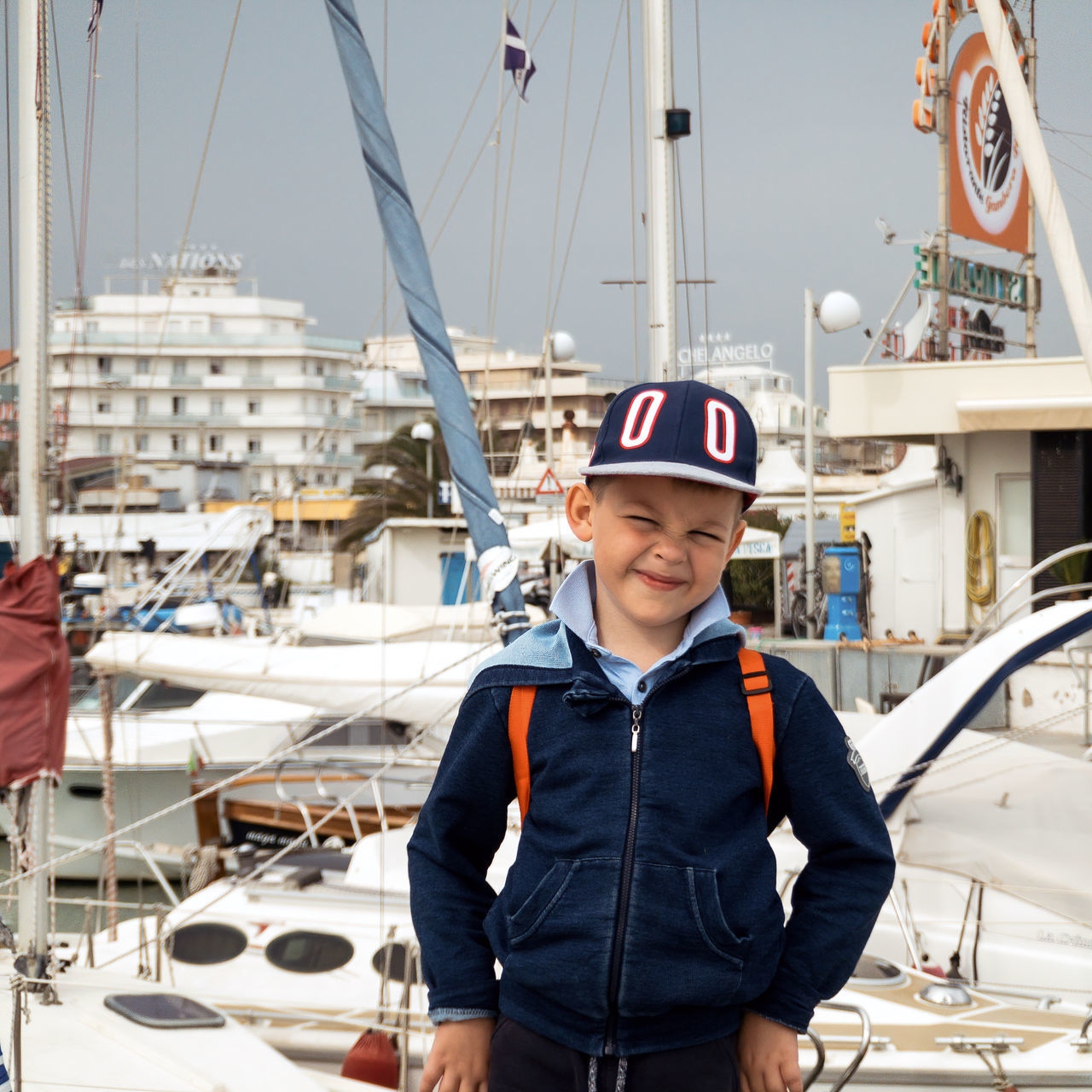 nautical vessel, looking at camera, men, boys, portrait, real people, transportation, mode of transportation, males, standing, smiling, child, one person, sailboat, front view, childhood, water, happiness, casual clothing, sailor, innocence