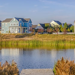 Houses by lake and buildings against sky