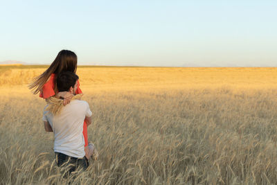 Rear view of woman standing on field against clear sky