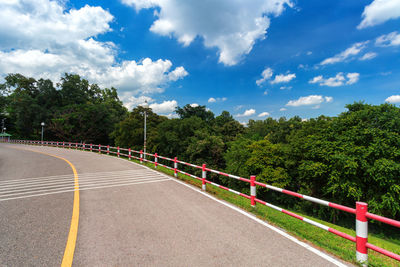 Road by trees against sky