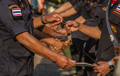 Midsection of military officers holding books and chain while standing outdoors