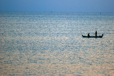 People on sea against clear sky