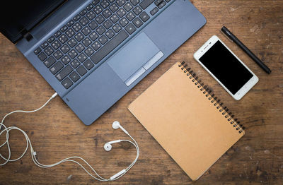 Directly above shot of laptop and pen by book on table