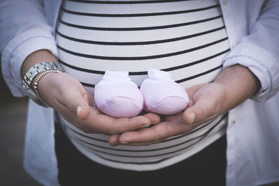 Midsection of pregnant woman holding baby booties
