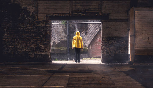 Rear view of woman standing against wall