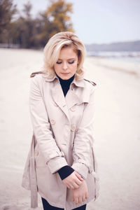 Portrait of beautiful woman standing at beach against sky