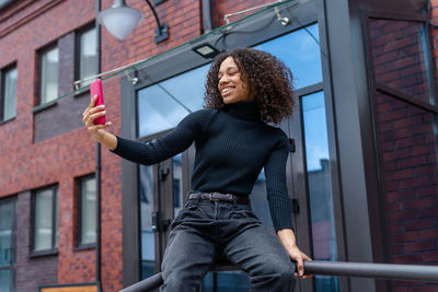 Portrait of young woman standing against building