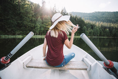 Rear view of woman sitting on boat sailing in lake