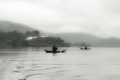 People on lake against sky