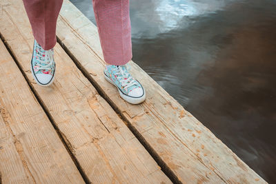 Low section of person standing on pier over lake