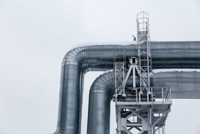 Low angle view of pipes of factory against clear sky