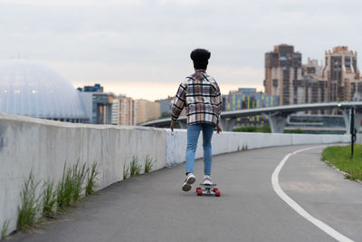 African skateboarder girl riding londboard over cityscape. female with afro hairstyle on skateboard