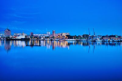 Reflection of factory in harbor against blue sky