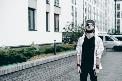 Man standing against buildings in city during rain