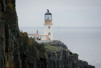 Neist point lighthouse on cliff in sea at isle of skye