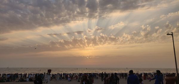 People on beach against sky during sunset