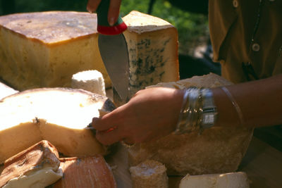 Close-up of woman cutting cheese on table