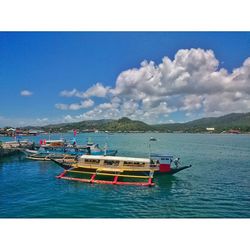 Boats in sea against cloudy sky