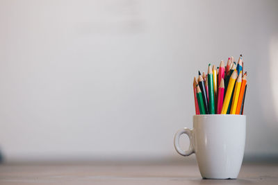 Close-up of multi colored pencils in cup on table