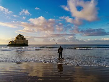 Man fishing in sea against sky