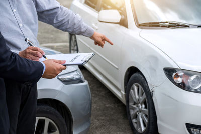 Midsection of man signing on car insurance paper