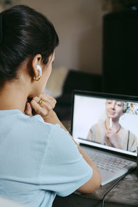 Female freelancer on video call with coworker over laptop while working at home office
