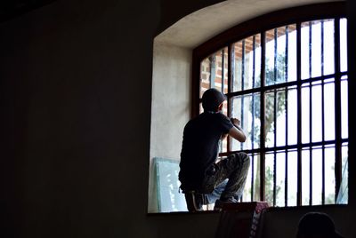 Rear view of man standing against window working contruccion