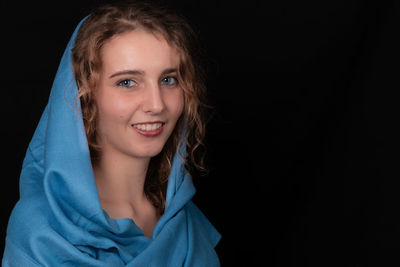 Portrait of smiling teenage girls standing against black background