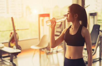 Young woman drinking water in gym