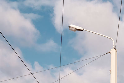 Streetlight and wires against cloudy sky