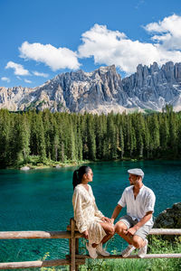 Couple sitting on mountain against sky