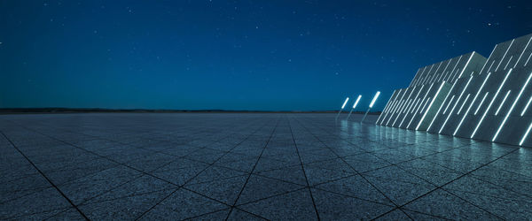 Empty road against clear blue sky at night