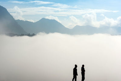 Rear view of silhouette men standing in front of fog