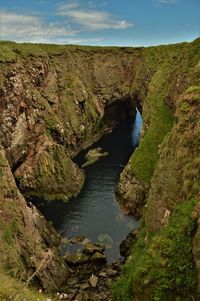 Scenic view of river by cliff against sky