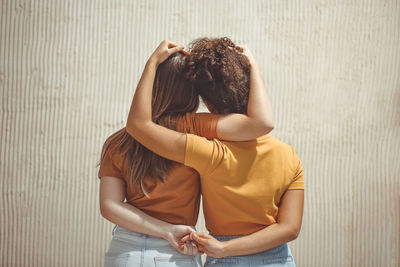 Rear view of woman standing against wall