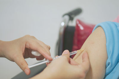 Cropped hands of doctor injecting on patient hand