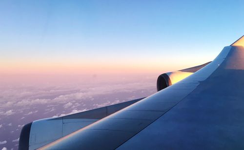 Airplane wing against sky during sunset