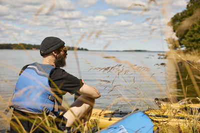 Man sitting and relaxing at lake near kayak